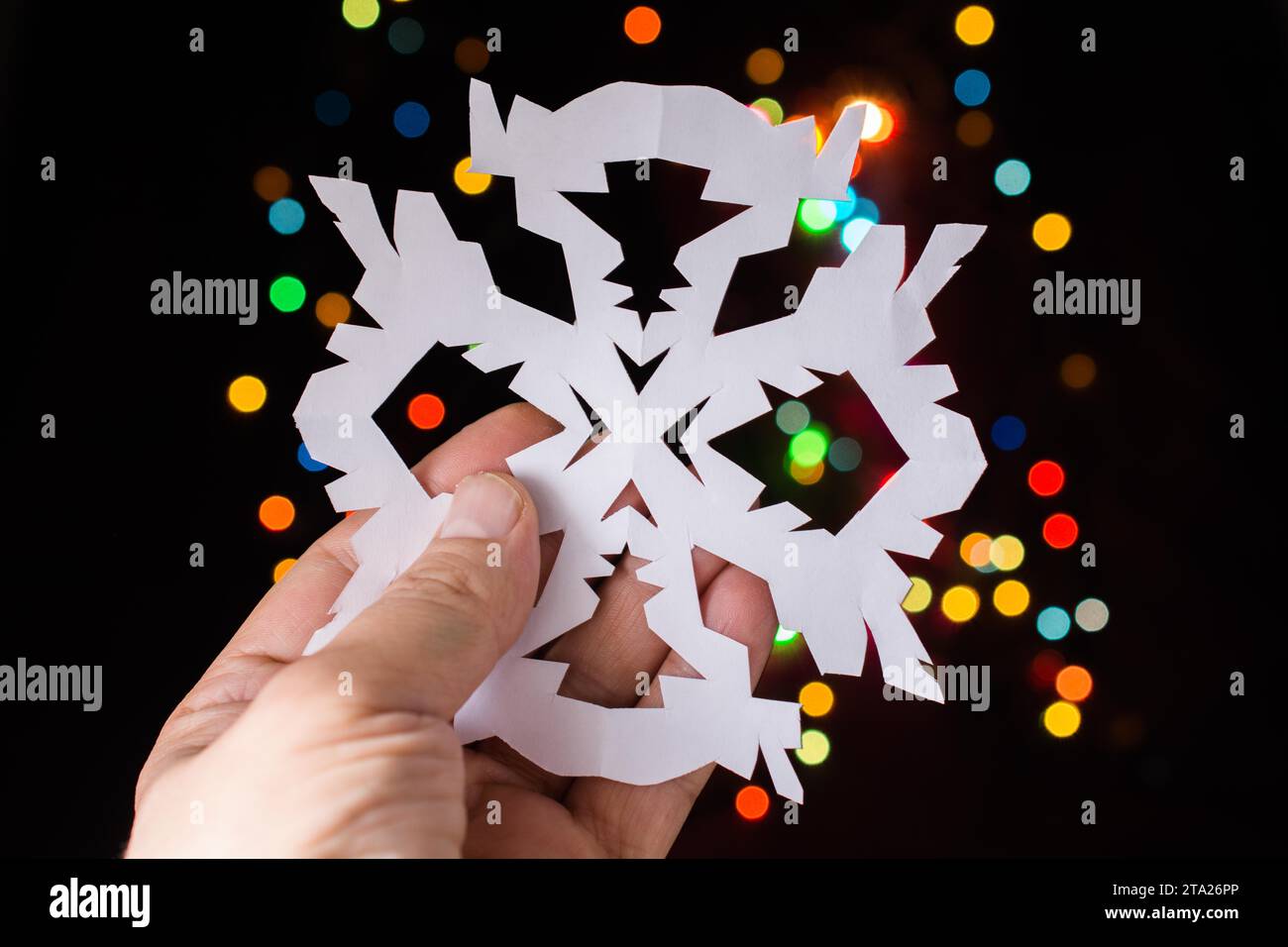 A forma di fiocco di neve con la carta in mano sul bokeh sfondo luminoso Foto Stock