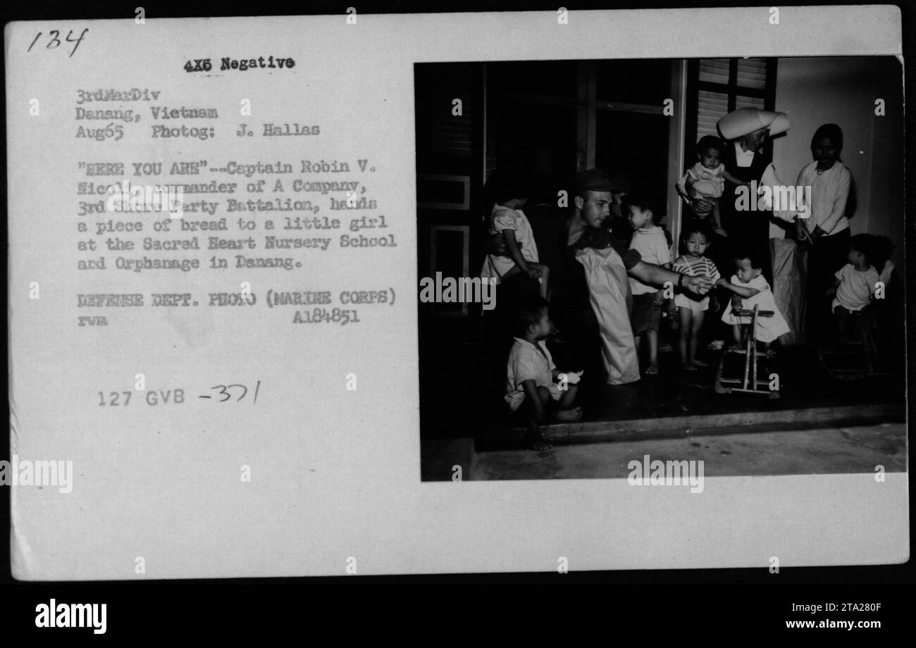 Nell'agosto 1965, il capitano Robin V. Icoli di Una compagnia, 3rd Shore Party Battalion, dà pane a una ragazza vietnamita alla Sacred Heart Nursery School e all'Orfanotrofio a Danang durante la guerra del Vietnam. Foto Stock