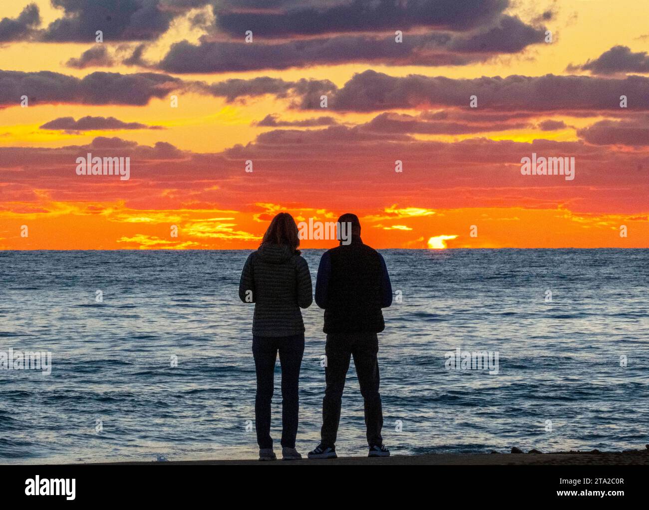 Una giovane coppia guarda il tramonto sul Mar Mediterraneo, Paphos, Cipro Foto Stock