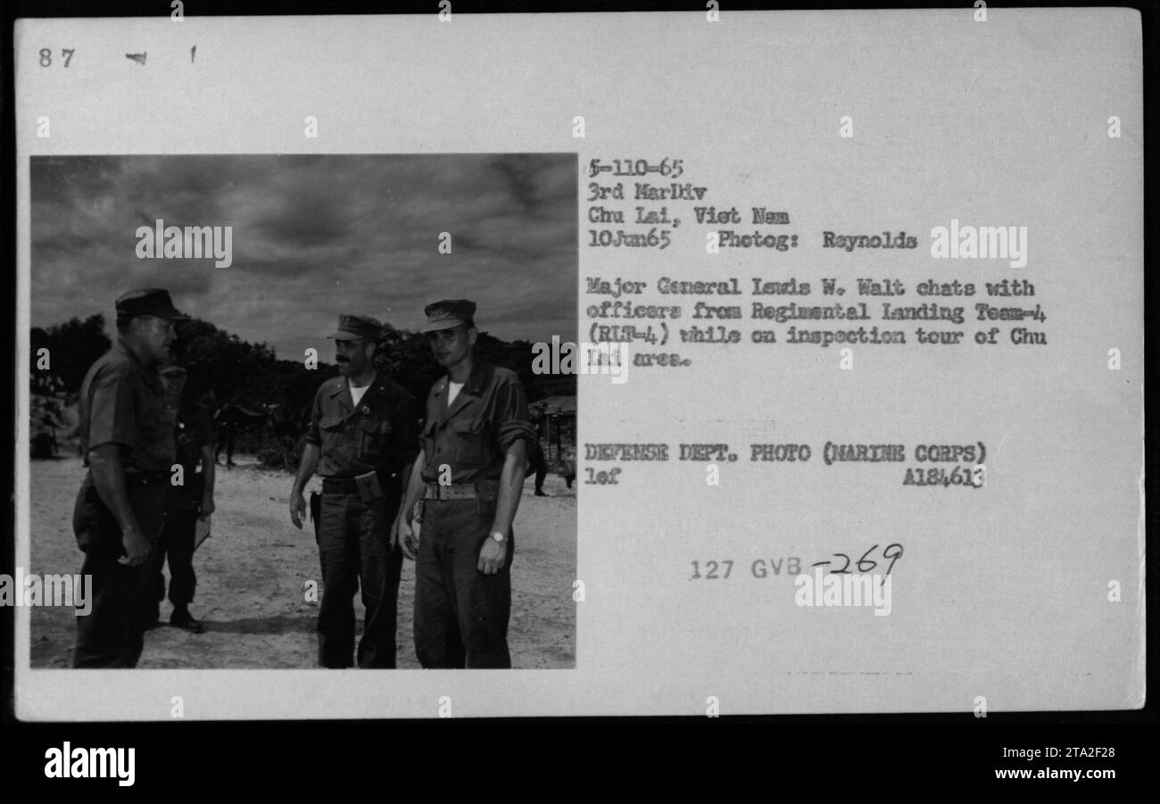 Il maggiore generale Leuds W. Walt dialoga con gli ufficiali del Regimental Landing Team-4 (RLT-4) durante un tour di ispezione di Chu Lai nella guerra del Vietnam. La fotografia, scattata da Reynolds il 10 giugno 1965, cattura la presenza di figure importanti come Robert McNamara, Richard Nixon e Billy Graham. Foto Stock