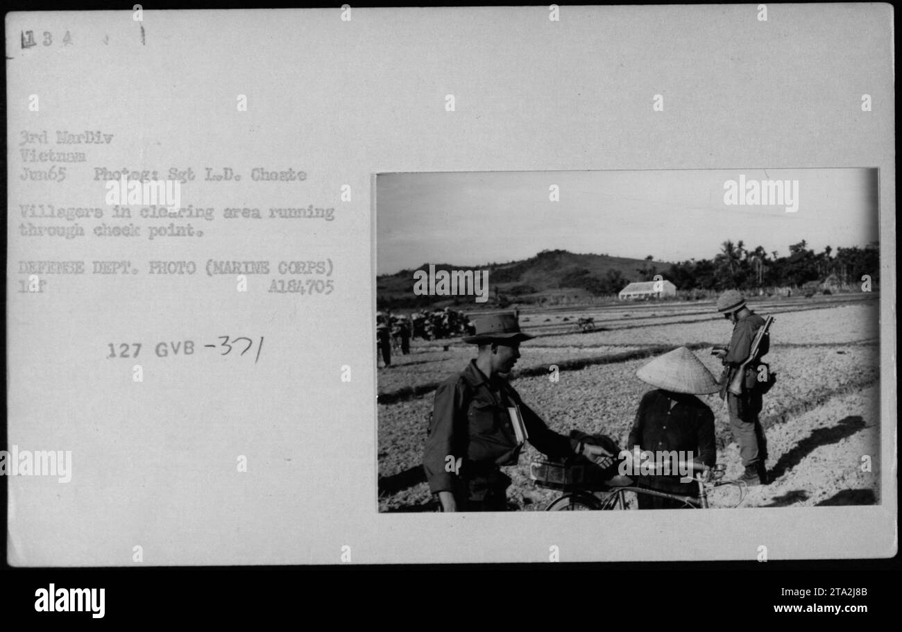 Gli abitanti del villaggio si precipitano attraverso un checkpoint in un'area di compensazione durante la guerra del Vietnam nel giugno 1965. Questa fotografia è stata scattata dal sergente L.D. Cheate e fa parte di una serie che documenta le attività militari americane durante la guerra. Foto Stock