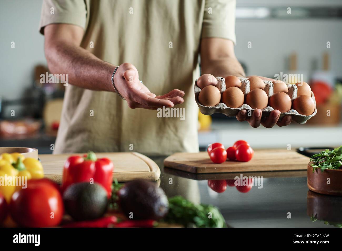 Primo piano di un uomo irriconoscibile che tiene una scatola di uova sopra il tavolo della cucina Foto Stock