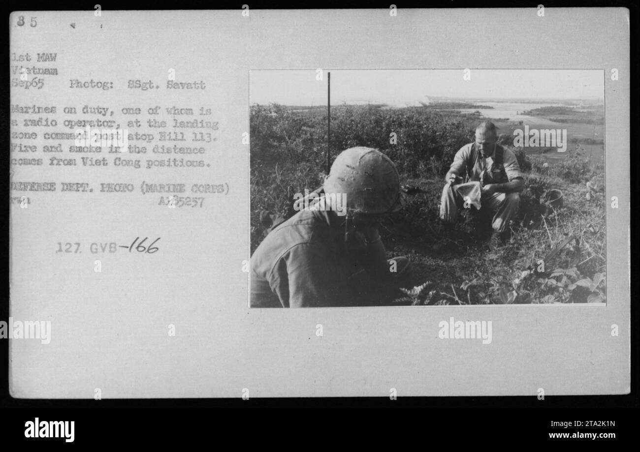 I Marines stazionarono al posto di comando della zona di sbarco sulla collina 113 durante la guerra del Vietnam. Un marine può essere visto azionare una radio mentre altri rimangono in servizio. In lontananza, fuoco e fumo sono visibili, probabilmente originati da posizioni Viet Cong. Questa foto è stata scattata nel settembre 1965. DIPARTIMENTO DIFESA FOTO (NUCLEI MARINI) A185257. Foto Stock