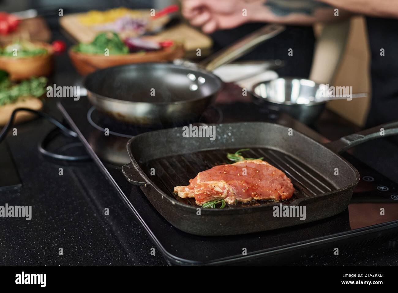 Primo piano sulla bistecca cruda che viene cucinata sul fornello elettrico in cucina, concentrati sulla bistecca Foto Stock