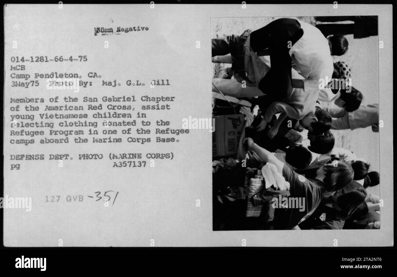I membri della Croce Rossa americana assistono i bambini vietnamiti nella scelta di abiti donati in un campo profughi a Camp Pendleton, California, il 3 maggio 1975. L'evento include apparizioni di Claudia Cardinale, Nguyen Cao Ky, Rosemary Clooney e Betty Ford, illustrando gli aiuti umanitari e il sostegno ai rifugiati durante le conseguenze della guerra del Vietnam. Foto Stock