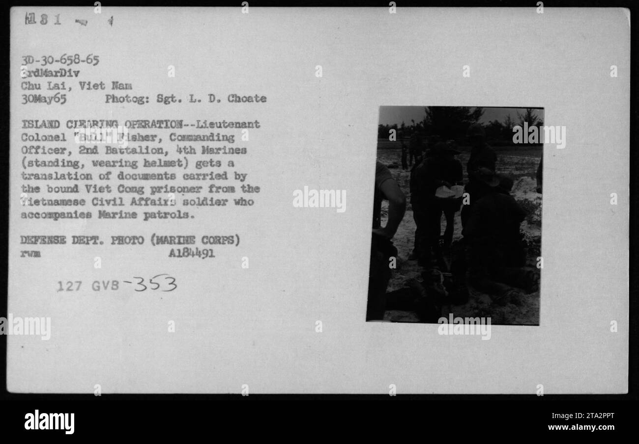 Didascalia: Il tenente colonnello 'Bull' Fisher, comandante del 2nd Battalion, 4th Marines, riceve una traduzione di documenti da un prigioniero Viet Cong vincolato durante un'operazione di sgombero dell'isola. La traduzione è fornita da un soldato vietnamita degli affari civili che accompagna le pattuglie dei Marine. Questa foto è stata scattata il 30 maggio 1965 a Chu Lai, come parte delle attività militari della guerra del Vietnam. Foto Stock