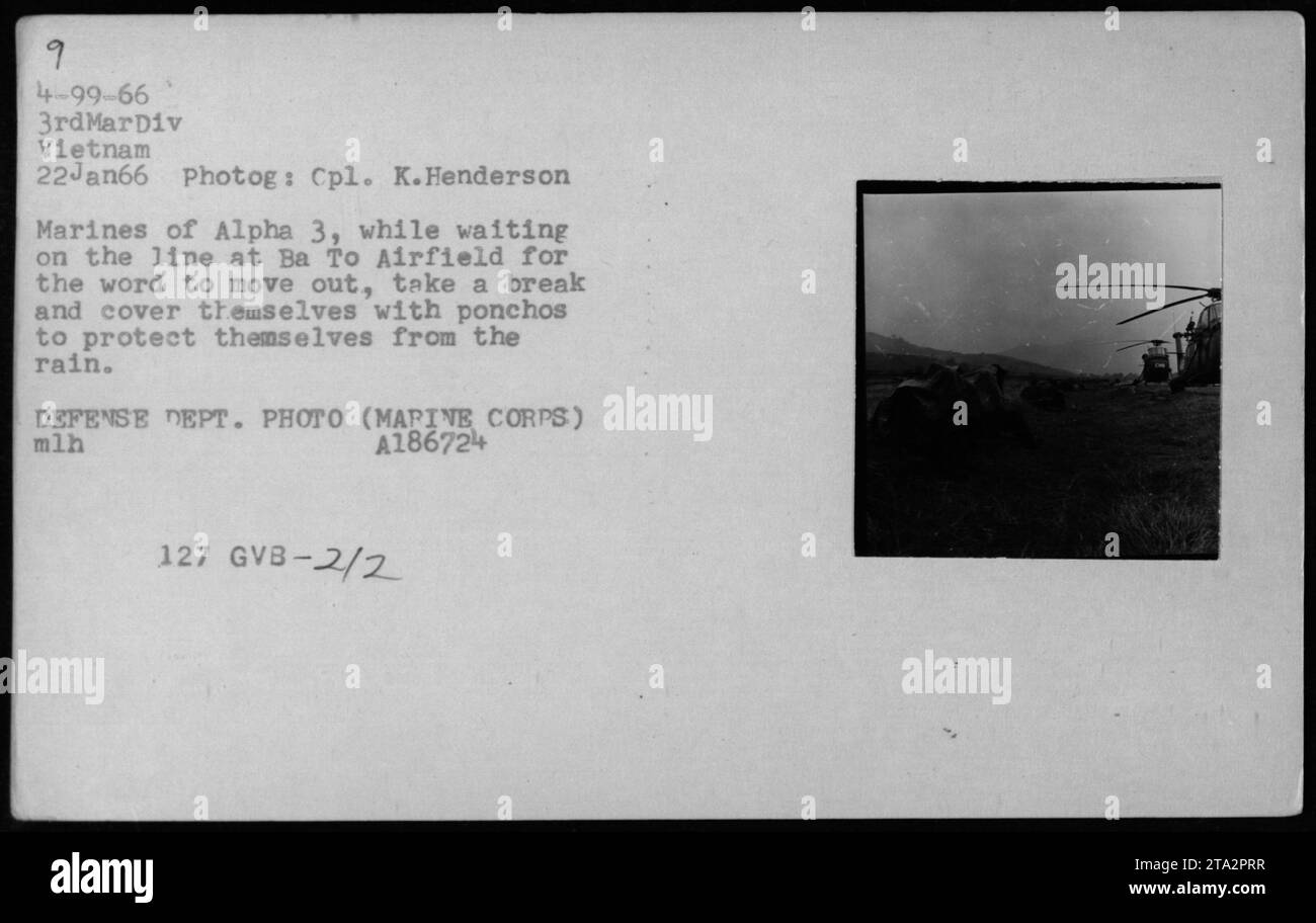 I Marines della divisione Alpha 3 di Ba to Airfield in Vietnam utilizzano poncho per proteggere la pioggia in attesa di ordini il 22 gennaio 1966. La foto è stata scattata dal colonnello K. Henderson per il Dipartimento della difesa, mostrando soldati in condizioni meteorologiche piovose durante la guerra del Vietnam. Foto Stock