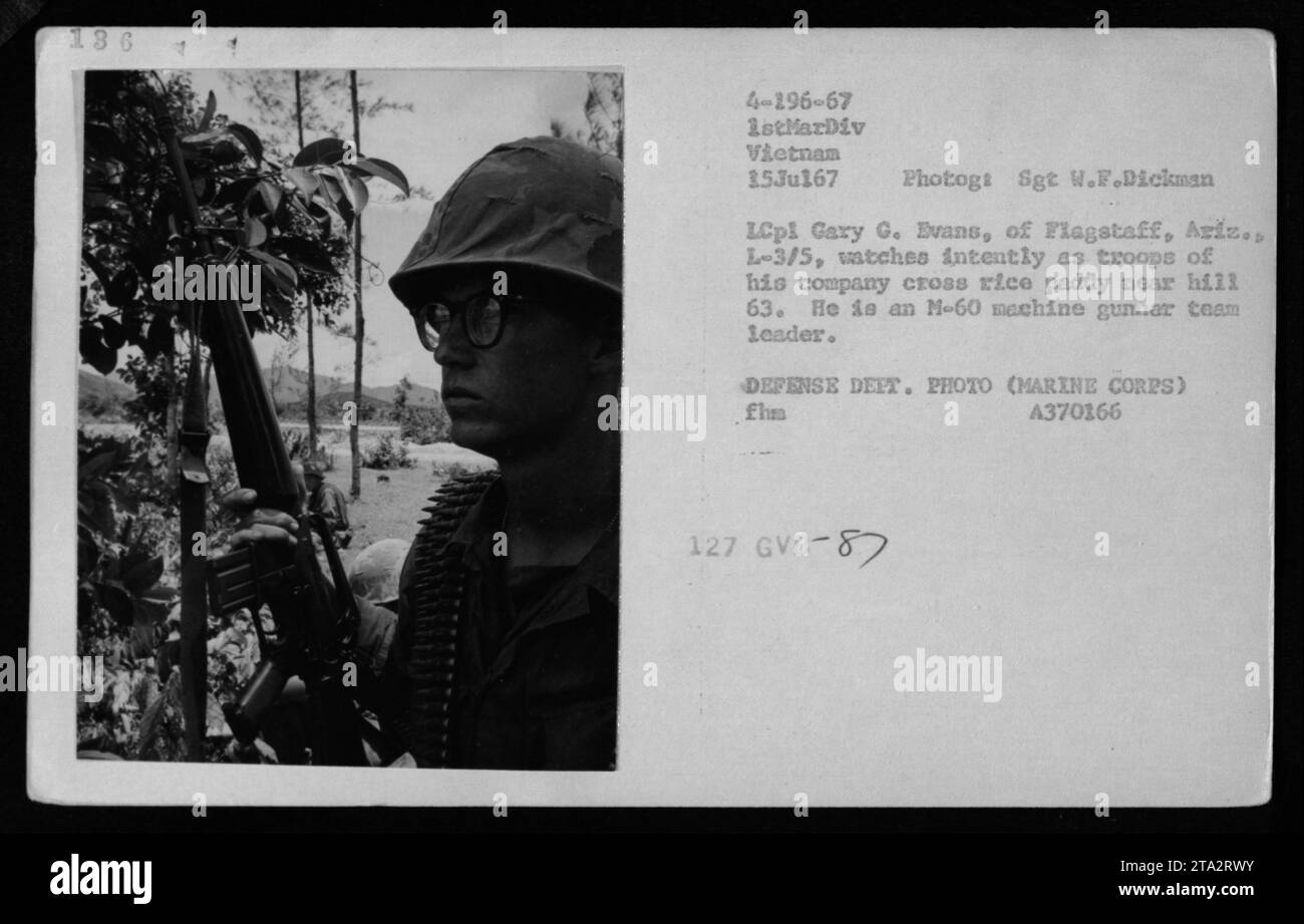 Lance caporale Gary G. Evans, leader del team di mitragliatrici L-3/5, guarda la sua compagnia attraversare una risaia vicino alla collina 63 in Vietnam il 15 luglio 1967 durante il combattimento. Foto Stock