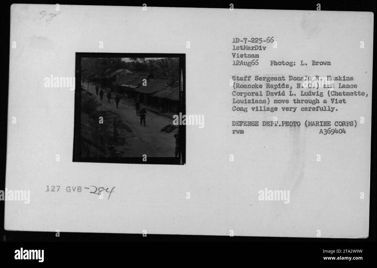 Il sergente dello staff dei Marines Donald R. Haskins (Roanoke Rapids, N. C.) e il caporale David L. Ludwig (Chatmette, Louisiana) navigano in un villaggio Viet Cong con cautela durante le pattuglie del 12 agosto 1966. Questa fotografia, scattata da L. Brown, cattura gli intensi e attenti movimenti dell'esercito americano durante la guerra del Vietnam. Foto Stock
