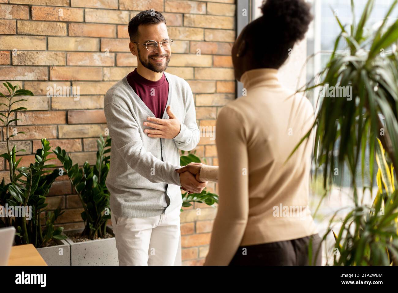Bella giovane coppia multietnica d'affari che stringe le mani nell'ufficio moderno Foto Stock
