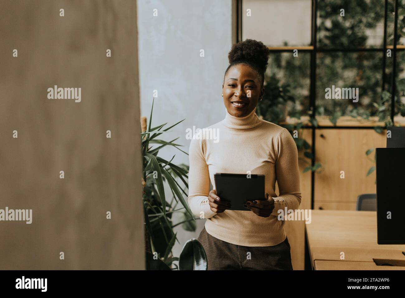 Giovane donna afroamericana in piedi con un tablet digitale in ufficio Foto Stock
