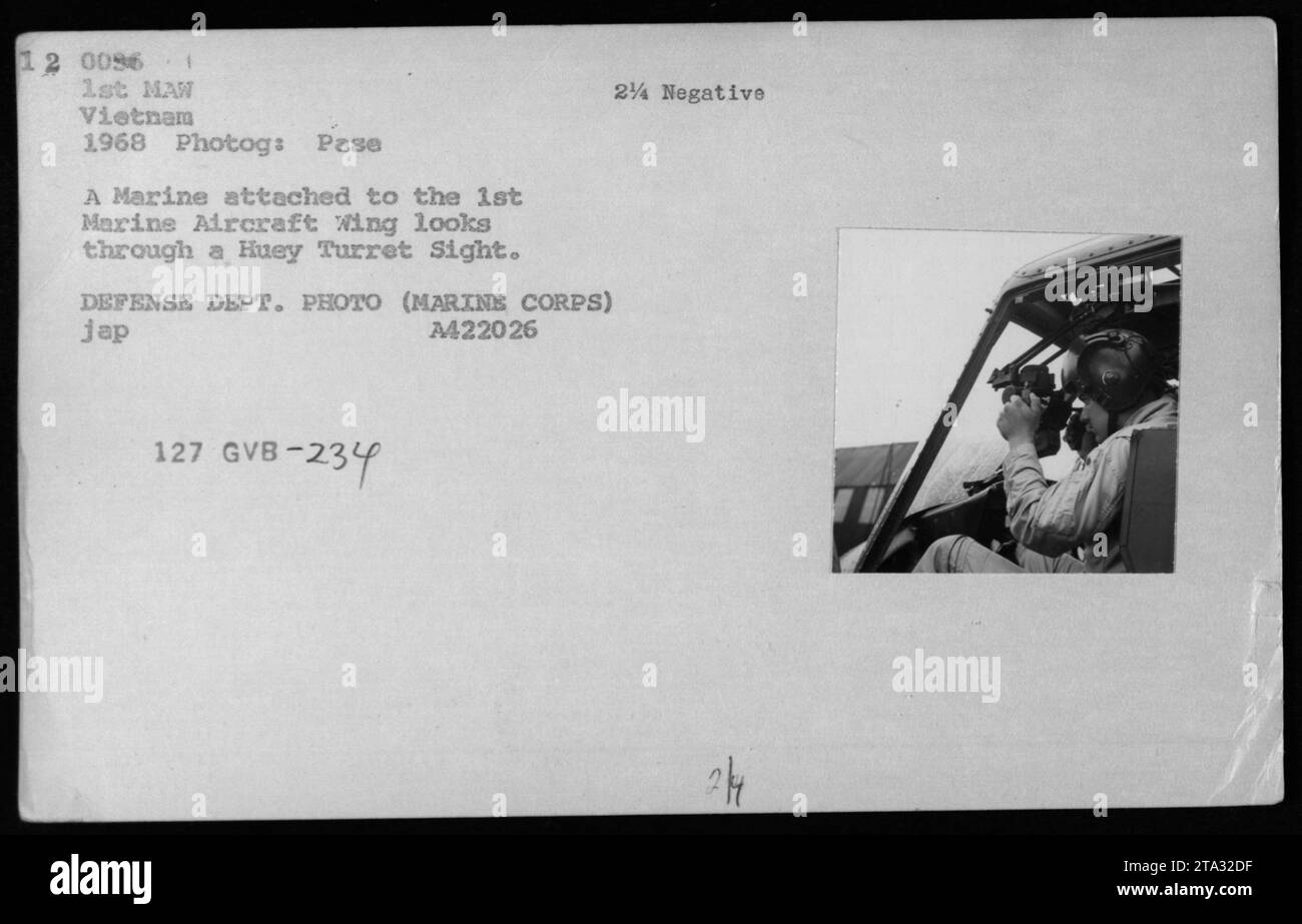 Un Marine attaccato al 1st Marine Aircraft Wing in Vietnam nel 1968 è visto guardando attraverso una Huey Turret Sight. La foto è stata scattata da Pase, un membro del Dipartimento della difesa. Anche Gregory 'Pappy' Boyington, un notevole pilota e membro dell'equipaggio, è presente nell'immagine, visitando il suo vecchio squadrone. Foto Stock