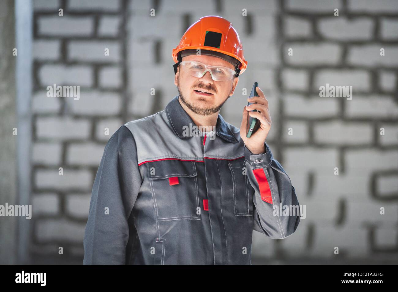 Un lavoratore professionista in cantiere che utilizza uno smartphone è sempre in contatto con il cliente o il caposquadra Foto Stock