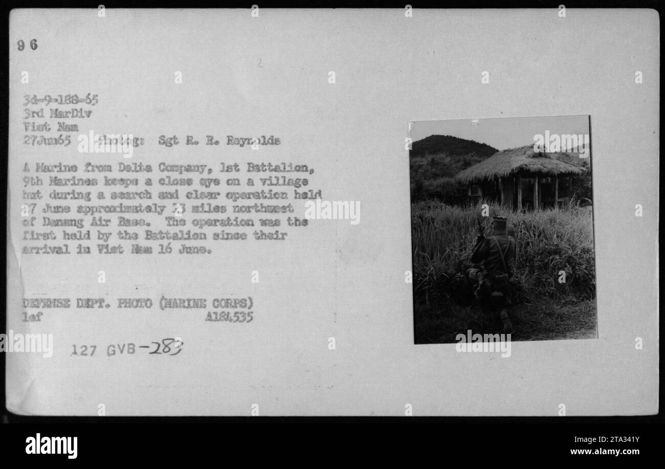 Un Marine della Delta Company, 1st Battalion, 9th Marines che sorvegliava una capanna del villaggio durante una ricerca e un'operazione chiara si tenne 13 miglia a nord-ovest della base aerea di Danang il 27 giugno 1965. Questa fu la prima operazione condotta dal Battaglione dal loro arrivo in Vietnam il 16 giugno. Foto Stock