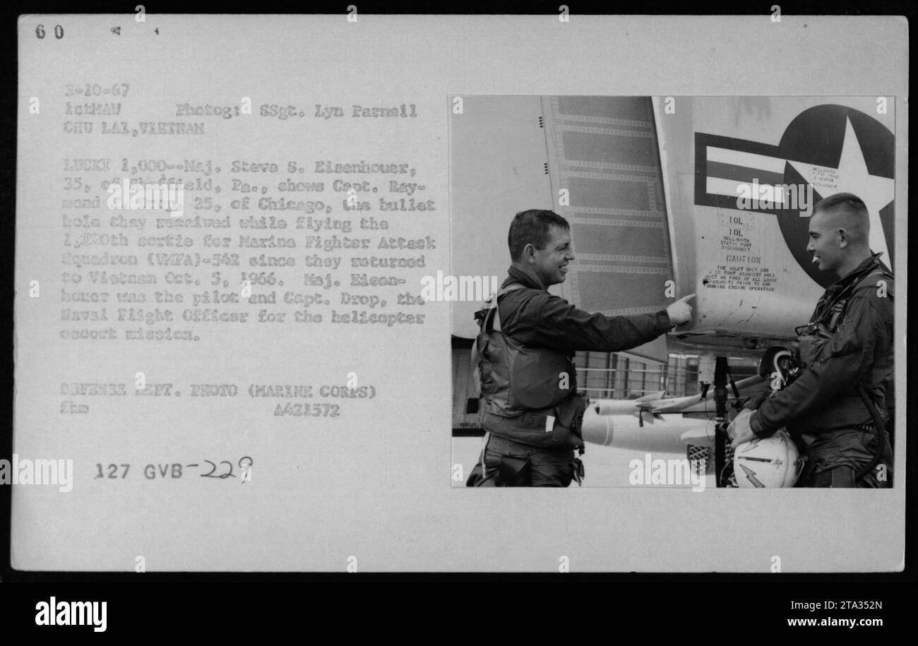 Il maggiore Steve S. Eisenhouer e il capitano Raymond J. Drop ispezionano una buca di proiettile dopo aver volato la 2.000 sortita del Marine Fighter Attack Squadron WFA-542 in Vietnam il 5 ottobre 1966 durante una missione di scorta in elicottero. Foto Stock