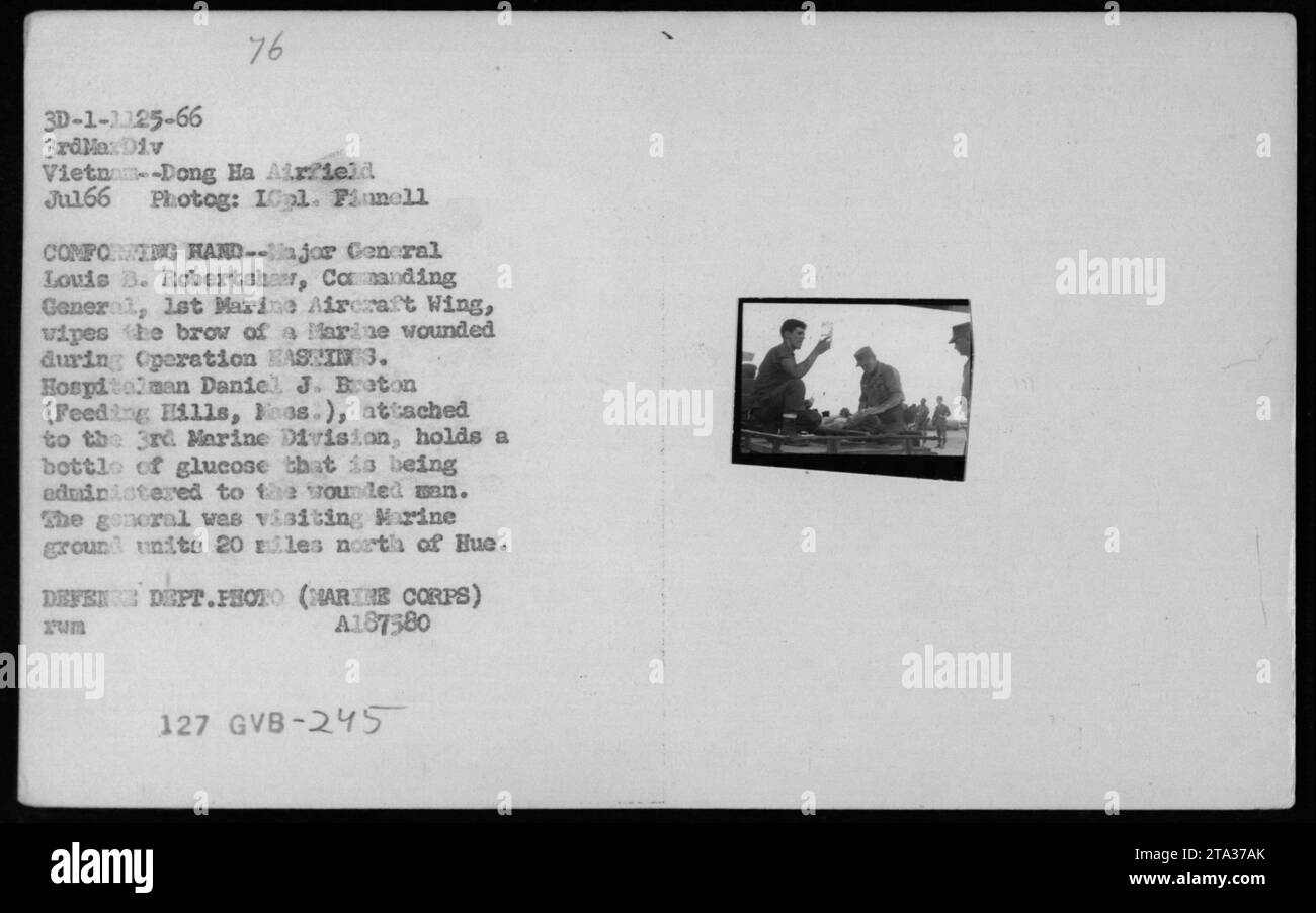 "Il maggiore generale Louis B. Robertsher, comandante generale del 1st Marine Aircraft Wing, pulisce la fronte di un Marine ferito durante l'operazione KASEINS3. L'ospedaliero Daniel J. Baton, Unito alla 3rd Marine Division, amministra glucosio all'uomo ferito. Il generale Robertsher stava visitando le unità terrestri marine vicino a Hue, in Vietnam, nel luglio 1966." Foto Stock