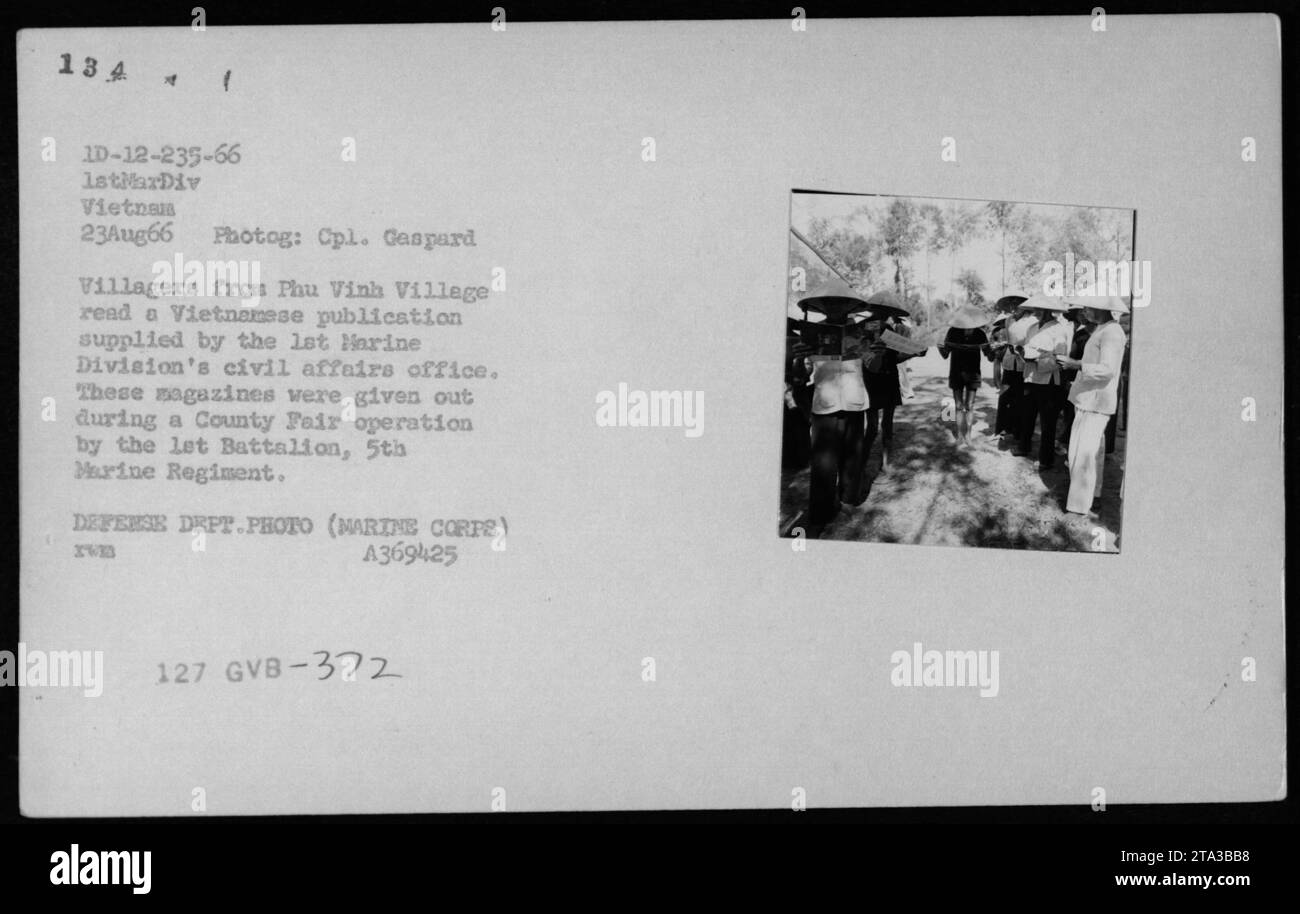 Civili vietnamiti nel villaggio di Phu Vinh leggendo le pubblicazioni vietnamite fornite dall'ufficio affari civili della 1st Marine Division durante una County Fair Operation condotta dal 1st Battalion, 5th Marine Regiment il 23 agosto 1966. Questa foto è stata scattata dal comandante Gaspard ed è una foto ufficiale del Dipartimento della difesa della guerra del Vietnam. Foto Stock