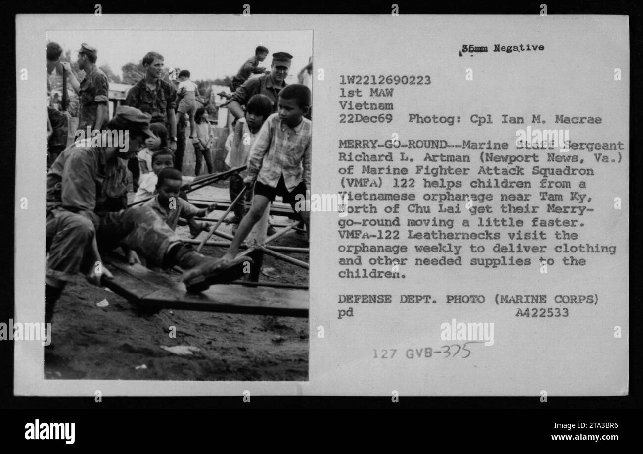 Il sergente dello staff marino Richard L. Artman del Marine Fighter Attack Squadron 122 assiste i bambini di un orfanotrofio vietnamita vicino a Tam Ky, a nord di Chu Lai, nell'esecuzione di un giostra. VMFA-122 visita regolarmente l'orfanotrofio, fornendo abbigliamento e provviste necessarie ai bambini. Presa il 22 dicembre 1969 da Ian M. Macrae. Foto Stock
