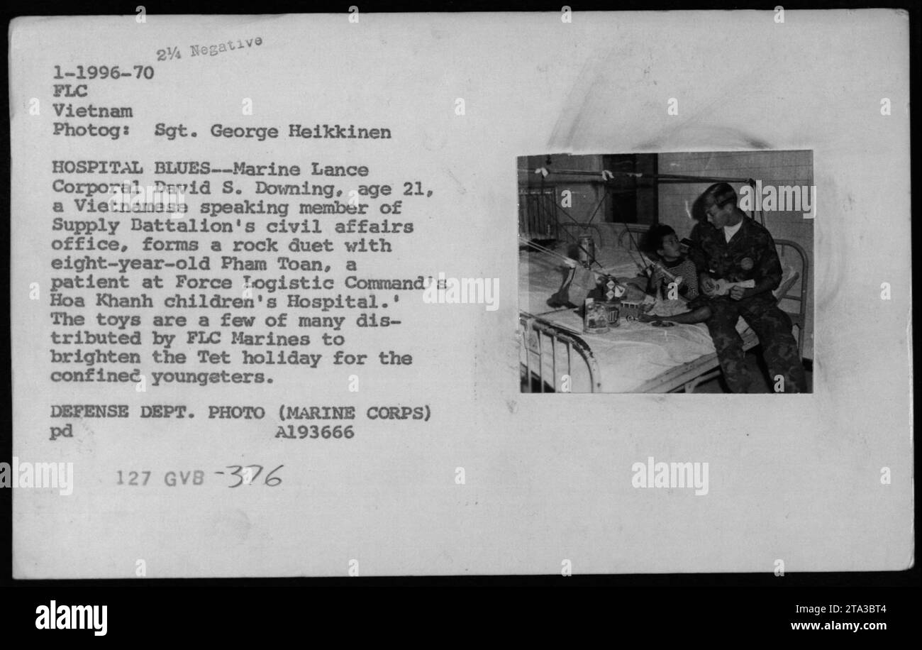 Il caporale dei Marine Lance David S. Downing canta un duetto con il paziente di otto anni Pham Toan all'Hoa Khanh Children's Hospital durante la guerra del Vietnam nel 1970. I giocattoli sono stati distribuiti dalla FLC Marines durante le vacanze Tet per sostenere il morale dei civili. Fotografia del sergente George Heikkinen. Foto Stock