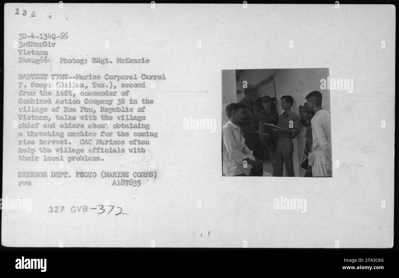 Il caporale Carrol P. Scape della Combined Action Company 32 si consulta con il capo del villaggio e con gli anziani a Hoa Phu, in Vietnam, il 24 agosto 1966, riguardo ad una trebbiatrice per la raccolta del riso, dimostrando la cooperazione civile-militare. Foto Stock