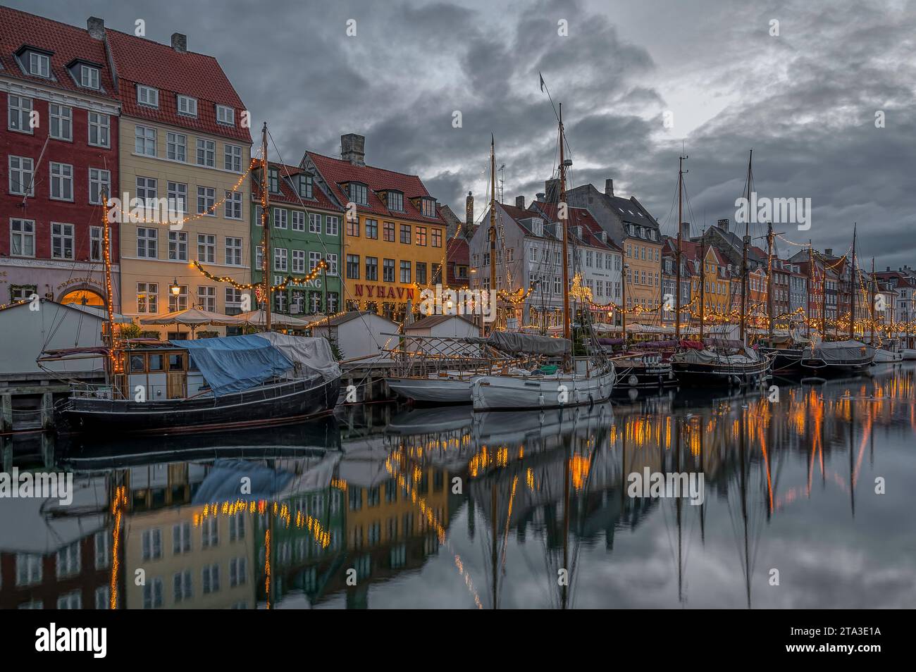 Barche da pesca tra le scintillanti decorazioni natalizie nel canale Nyhavn di Copenhagen, 25 novembre 2023 Foto Stock