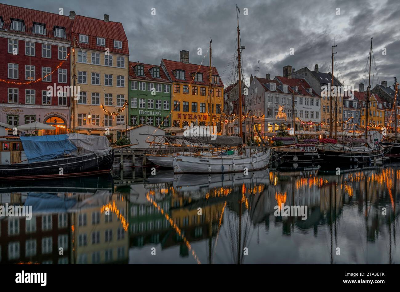 Le deocorazioni natalizie si riflettono nel canale Nyhavn di Copenaghen al crepuscolo, 25 novembre 2023 Foto Stock