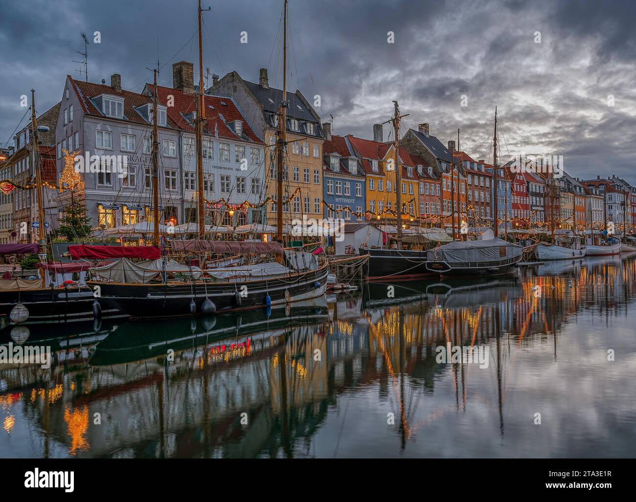 Le deocorazioni natalizie si riflettono nel canale Nyhavn di Copenaghen al crepuscolo, 25 novembre 2023 Foto Stock