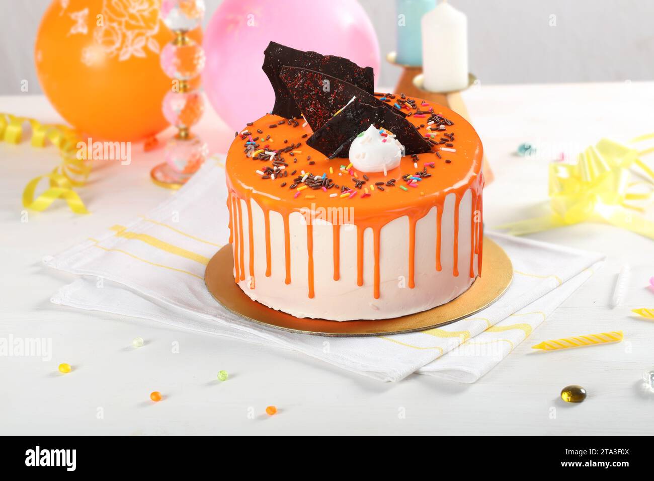 Striscione arancione con sfondo chiaro e decorazioni per feste. Copia spazio. Concetto di celebrazione. Drip cake alla moda. Messa a fuoco selettiva. Foto Stock