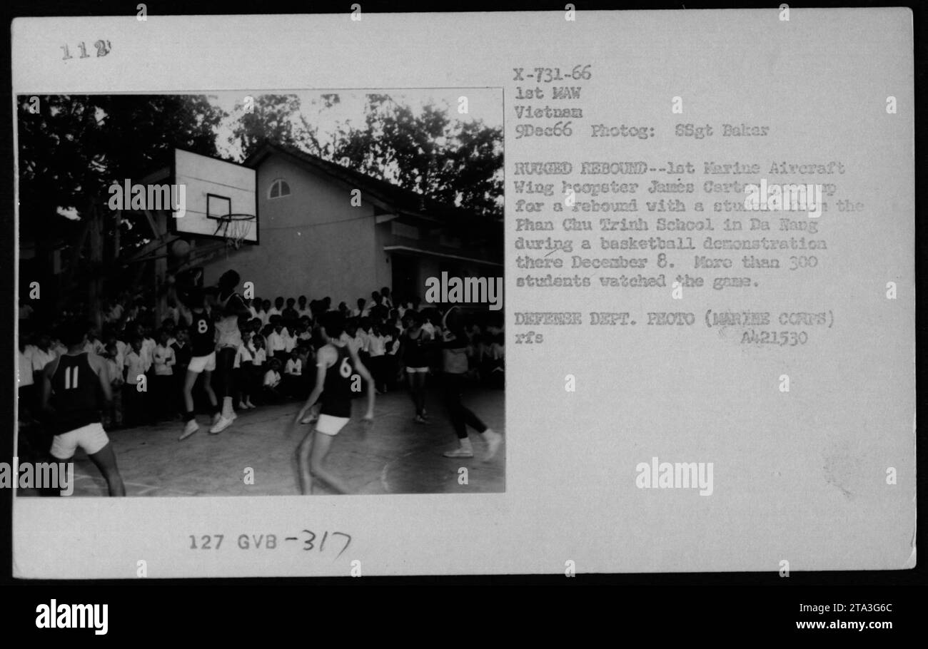 Il 9 dicembre 1966, James Carter partecipa a una dimostrazione di basket con uno studente della Than Chu Trinh School di da Nang durante un'attività di riposo e relax. Oltre 300 studenti hanno guardato la partita, mostrando il coinvolgimento tra il personale militare americano e le comunità locali durante la guerra del Vietnam. Foto Stock