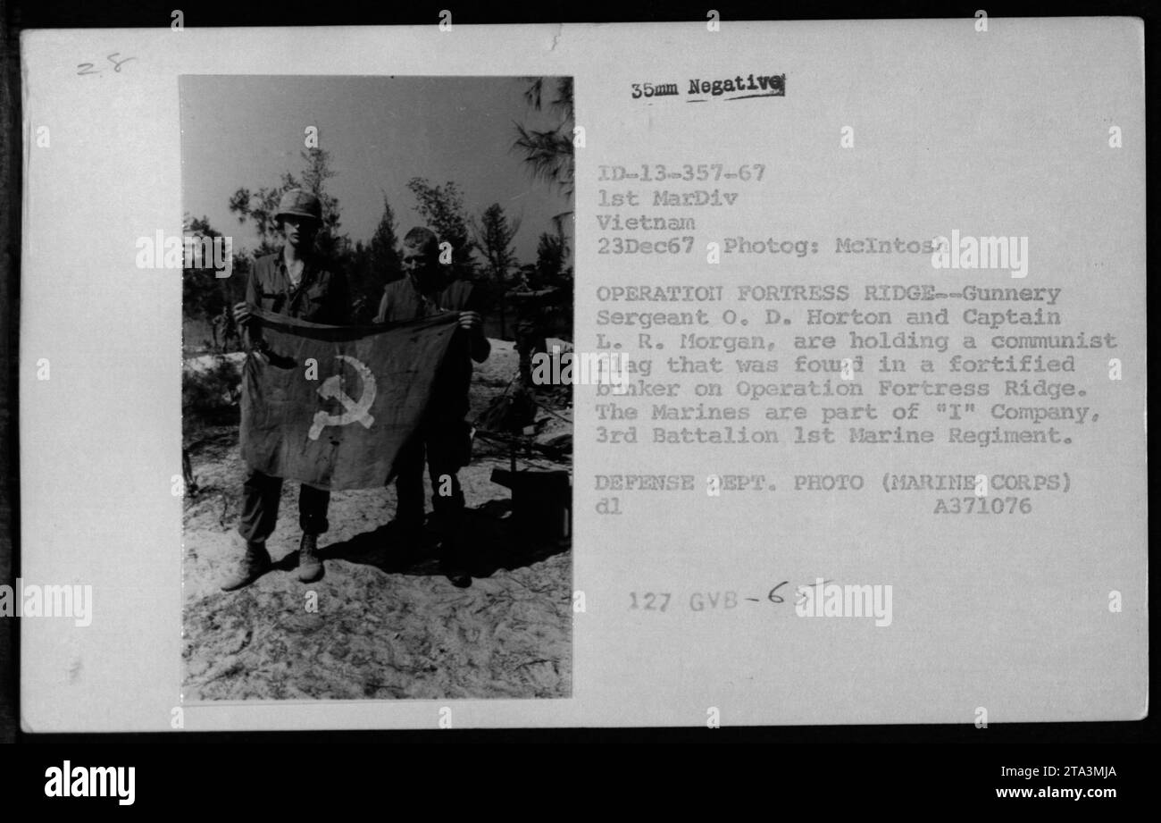 Il sergente O.D. Horton e il capitano L.R. Morgan mostrano una bandiera comunista trovata in un bunker fortificato durante l'operazione Fortress Ridge il 23 dicembre 1967 in Vietnam. La foto, scattata da McIntosh, mostra i Marines della compagnia 'i', 3rd Battalion 1st Marine Regiment. Foto del Dipartimento della difesa, corpo dei Marines. [Fonte: A371076, 2,8 35mm negativo ID-13-357-67, 1st MarDiv Vietnam] Foto Stock