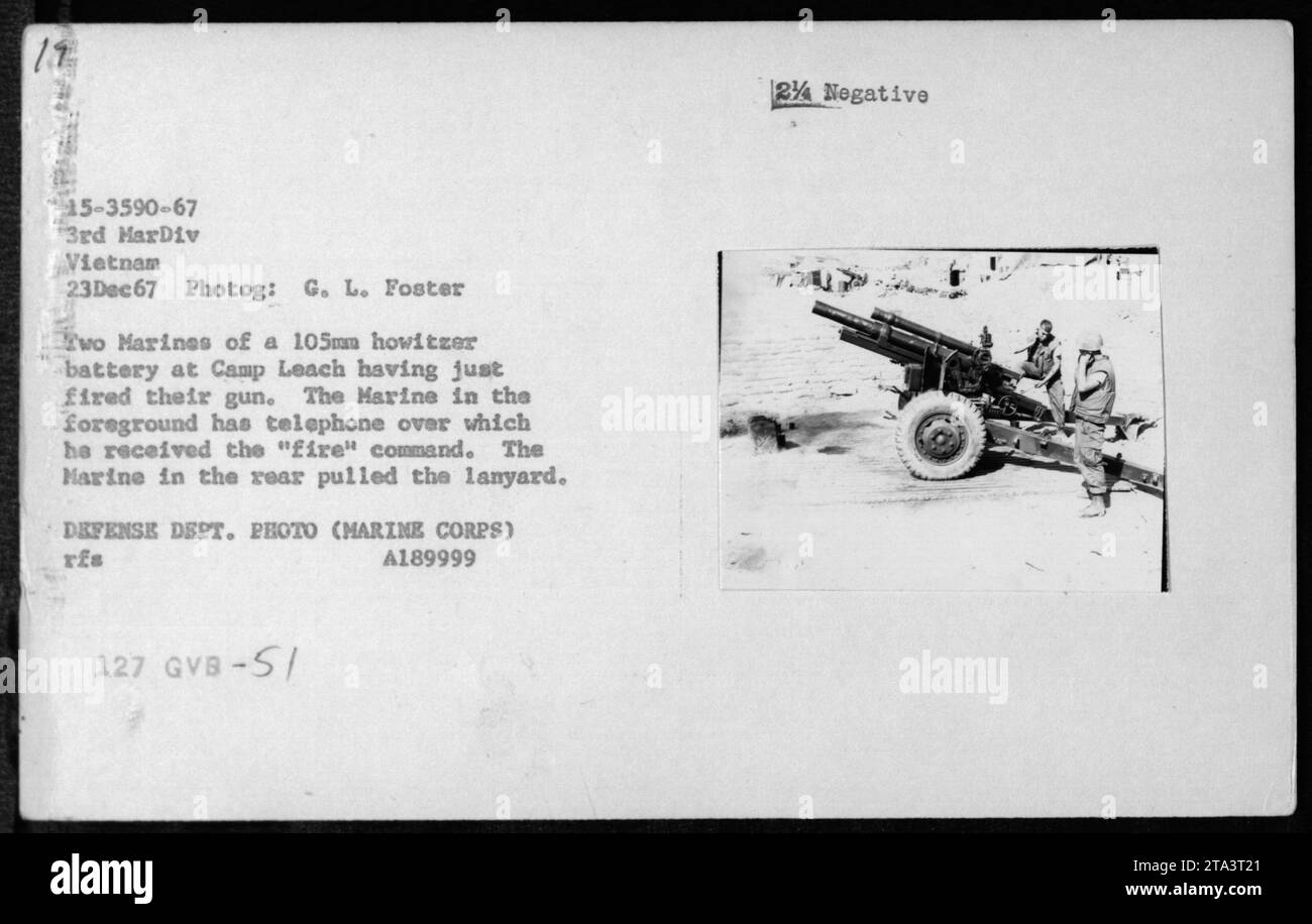 Due marines in una batteria da 105 mm a Camp Leach, in Vietnam, vengono visti dopo aver sparato con la loro pistola. Il sottomarino in primo piano può essere visto utilizzando un telefono per ricevere il comando di "fuoco", mentre il sottomarino nella parte posteriore viene mostrato mentre tira il cordone. Questa fotografia è stata scattata il 23 dicembre 1967 e fa parte della collezione che documenta le attività militari americane durante la guerra del Vietnam. Foto Stock