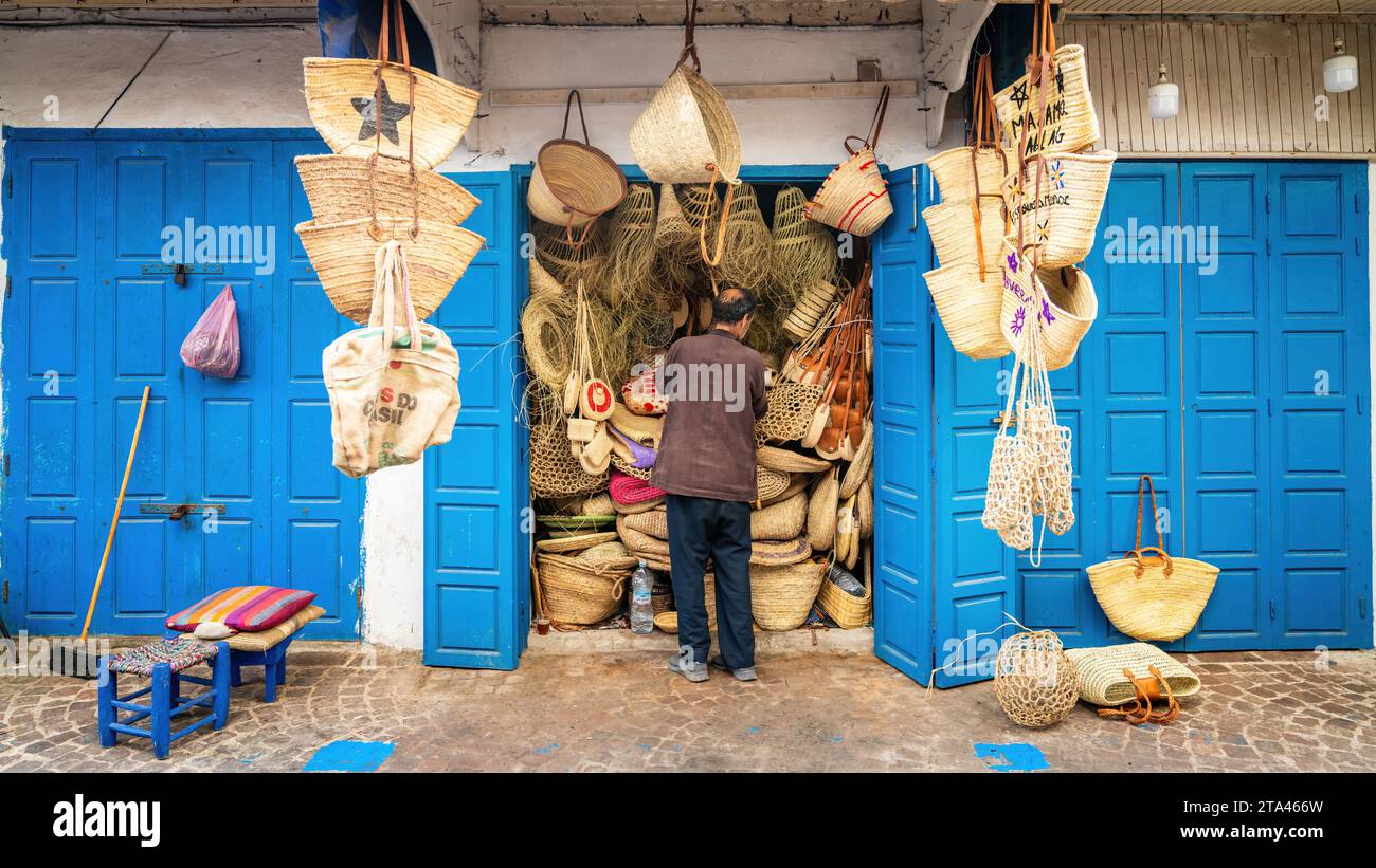 Essaouira, Marocco - 17 settembre 2022: Uomo marocchino apre il suo negozio al mattino, dove vende borse e cesti tradizionali nella città di Essaouira, mar Foto Stock