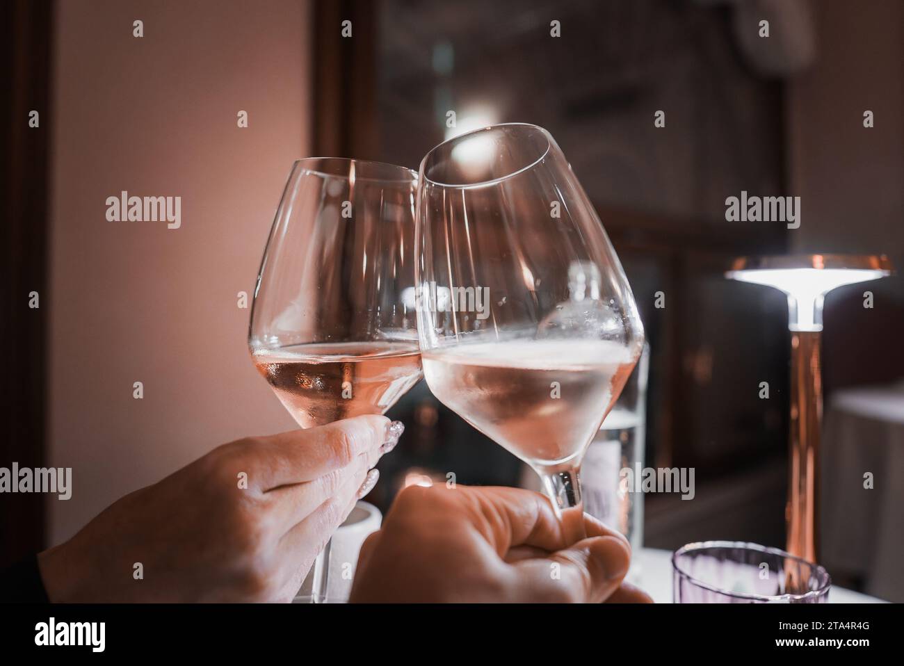 Romantico brindisi di coppia con bicchieri di vino bianco presso l'accogliente ristorante di Venezia, Italia Foto Stock