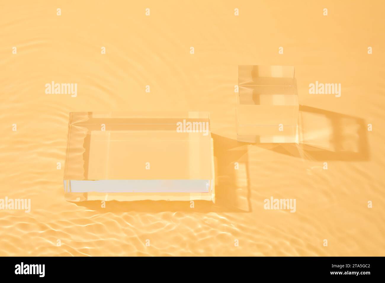 Cubo e podio rettangolare disposti su sfondo arancione. Scenografia minimalista con piattaforma a podio geometrica Foto Stock