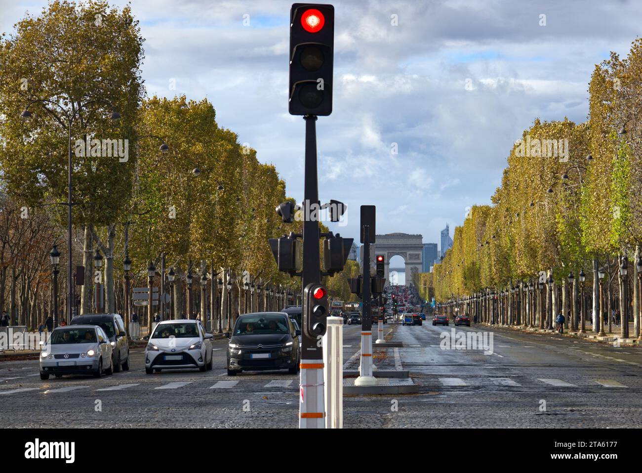 Parigi, Francia - auto in attesa al semaforo nell'affollato viale degli Champs Elysees, con l'Arco di Trionfo in lontananza Foto Stock