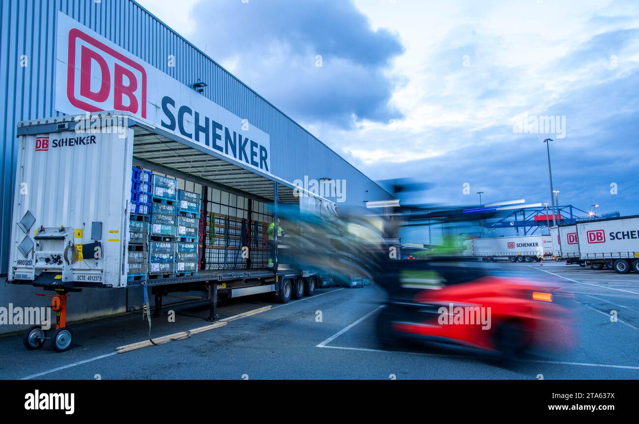 Rostock, Germania. 21 novembre 2023. I pallet e le merci trasportate vengono scaricati dai rimorchi della società di logistica DB Schenker sul sito del centro logistico nel porto marittimo. (Foto con un lungo periodo di esposizione) la filiale logistica di Deutsche Bahn gestisce diversi centri logistici nel Meclemburgo-Pomerania. Credito: Jens Büttner/dpa/Alamy Live News Foto Stock