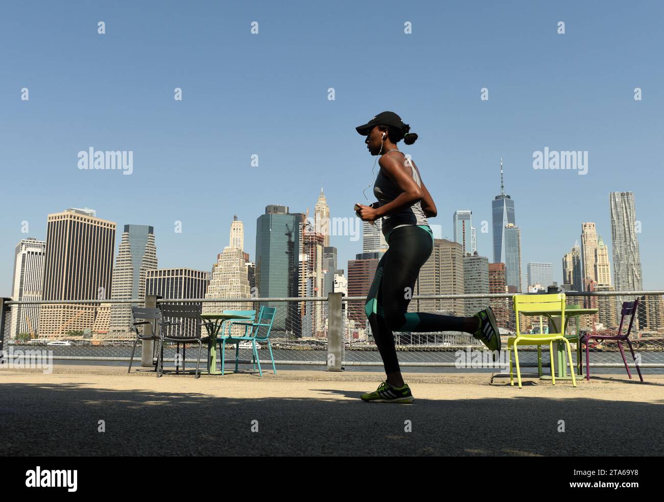 New York, USA - 25 maggio 2018: A Woman the run nel Brooklyn Bridge Park con il distretto finanziario di Lower Manhattan sullo sfondo. Foto Stock