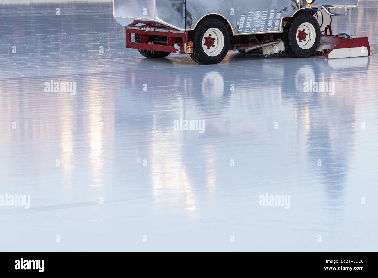 È in corso la lucidatura della pista di ghiaccio, mentre i macchinari per la ristrutturazione del ghiaccio sono in un'arena vuota Foto Stock
