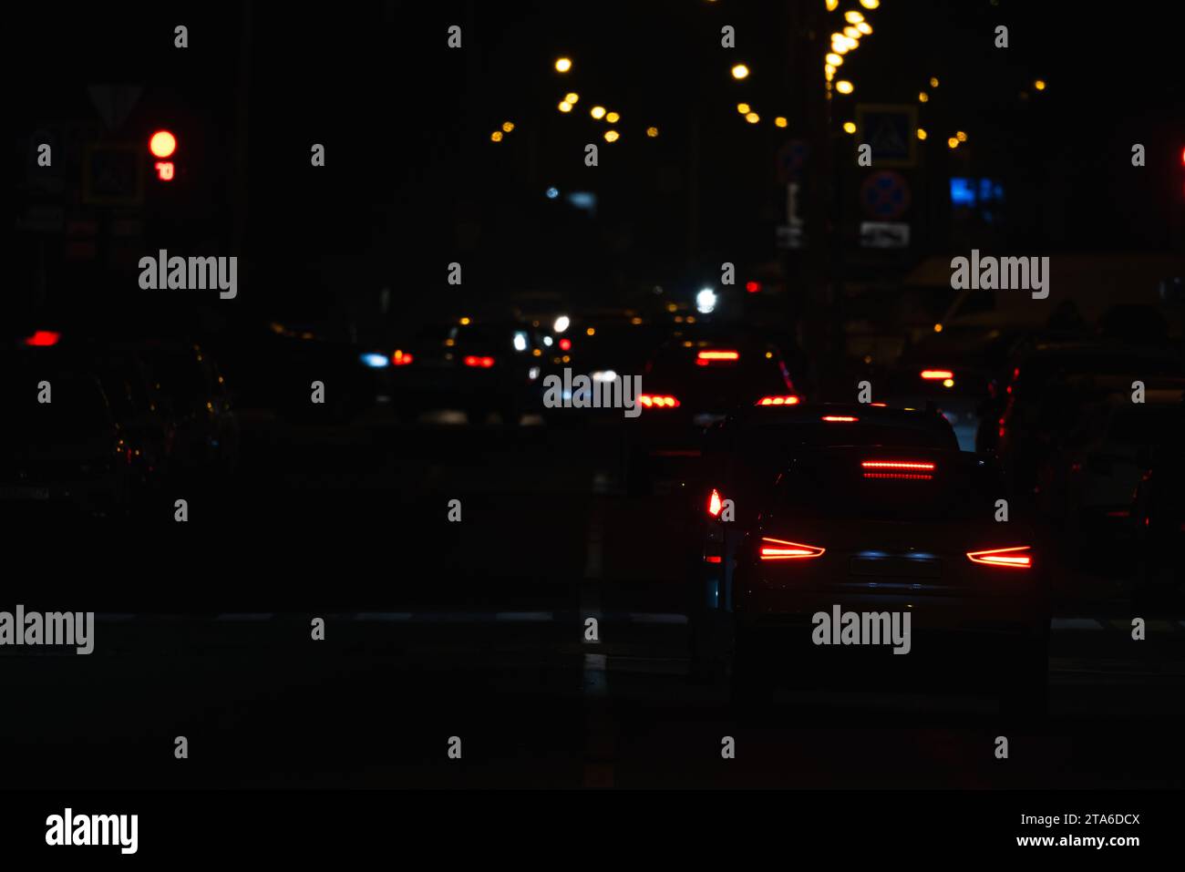 Vista notturna della città con auto su una strada e luci colorate Foto Stock