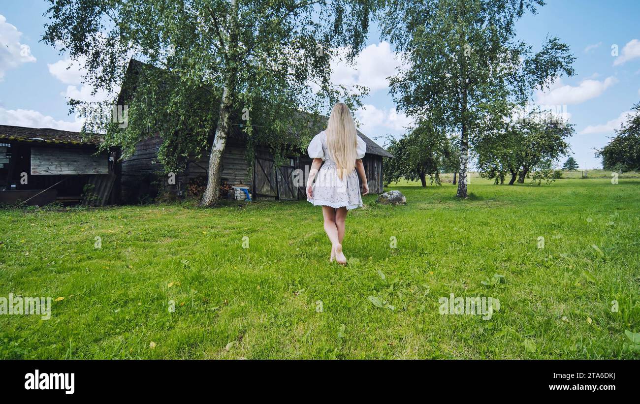 Una ragazza di aspetto slavo si pone in campagna vicino al fienile. Foto Stock