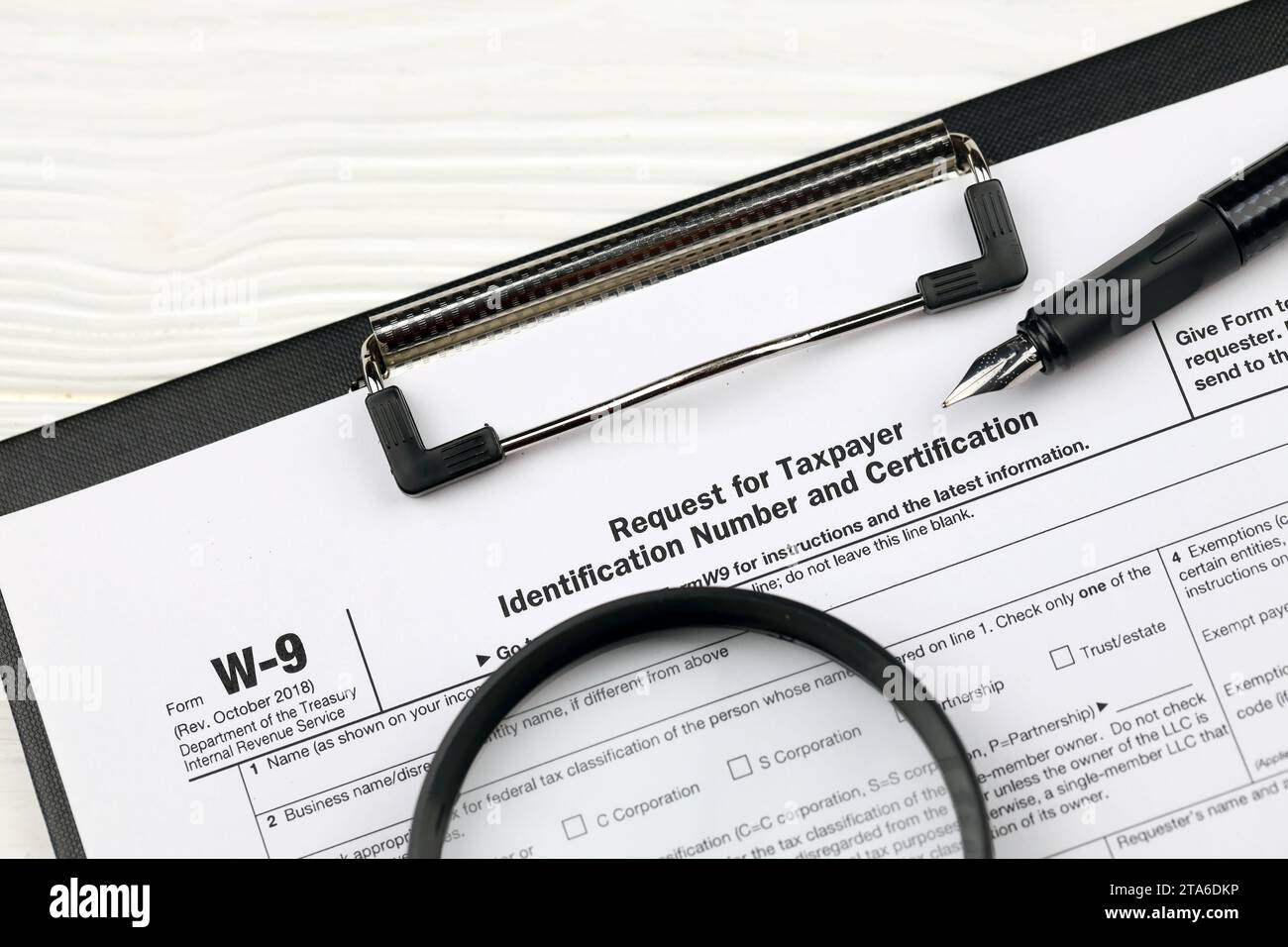 Modulo IRS W-9 richiesta di numero di identificazione contribuente e certificazione, il vuoto su tablet A4 si trova sul tavolo dell'ufficio con penna e lente di ingrandimento in primo piano Foto Stock