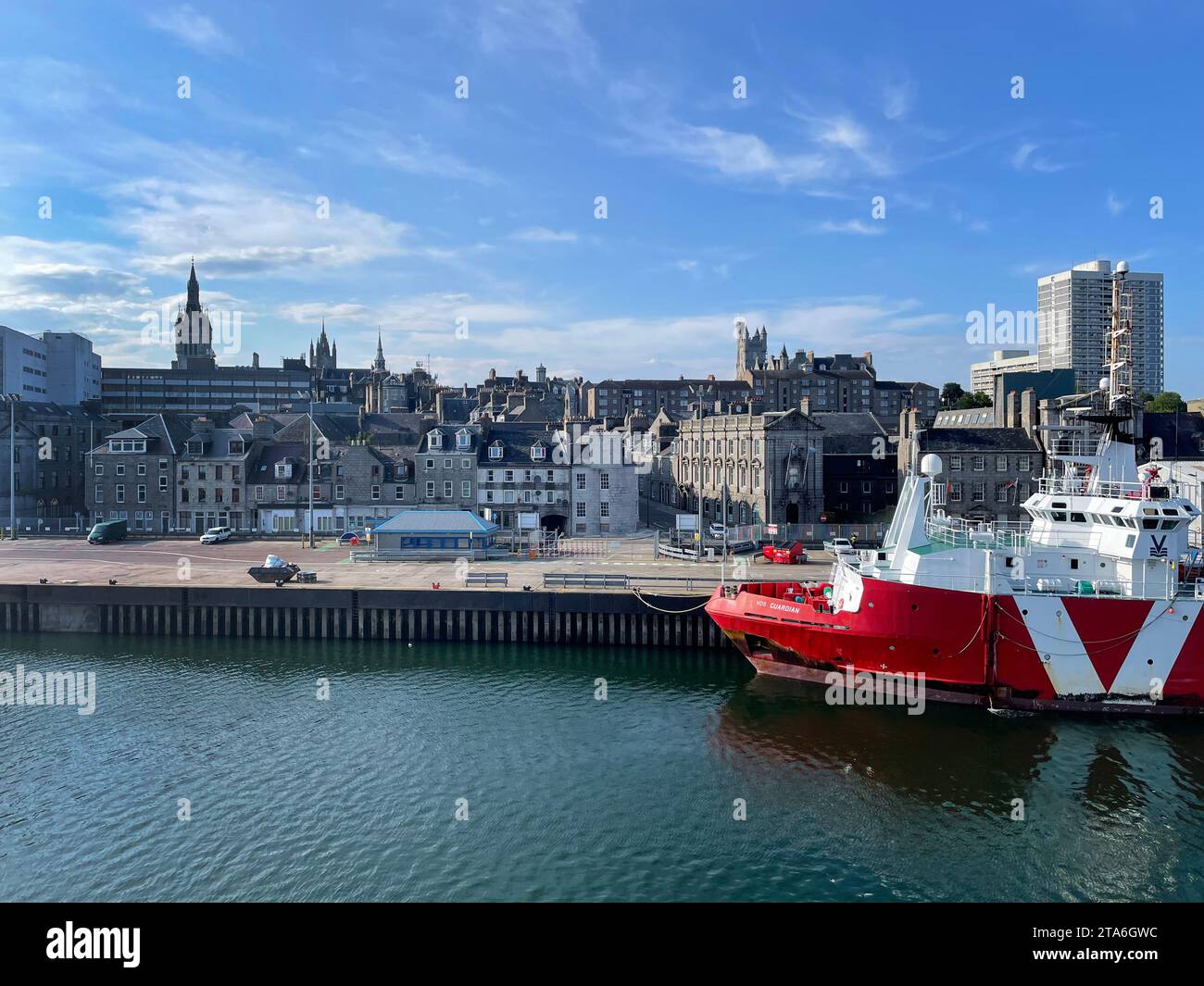 Nave di sicurezza standby chiamata VOS Guardian con il suo scafo rosso in attesa accanto al porto di Aberdeen con la città visibile sullo sfondo Foto Stock