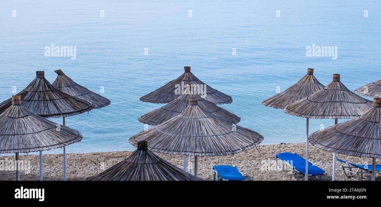 Ombrelloni con tetto in paglia e sdraio sulla spiaggia. Spiaggia vuota con ombrelloni e lettini. Spiaggia senza gente. idea di concetto per vacanza, vacanza Foto Stock