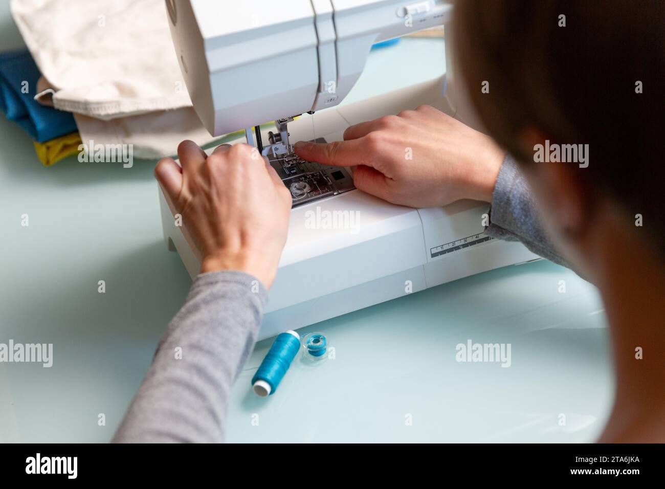 Primo piano delle mani femminili di Tailor che preparano la macchina da cucire. Foto Stock
