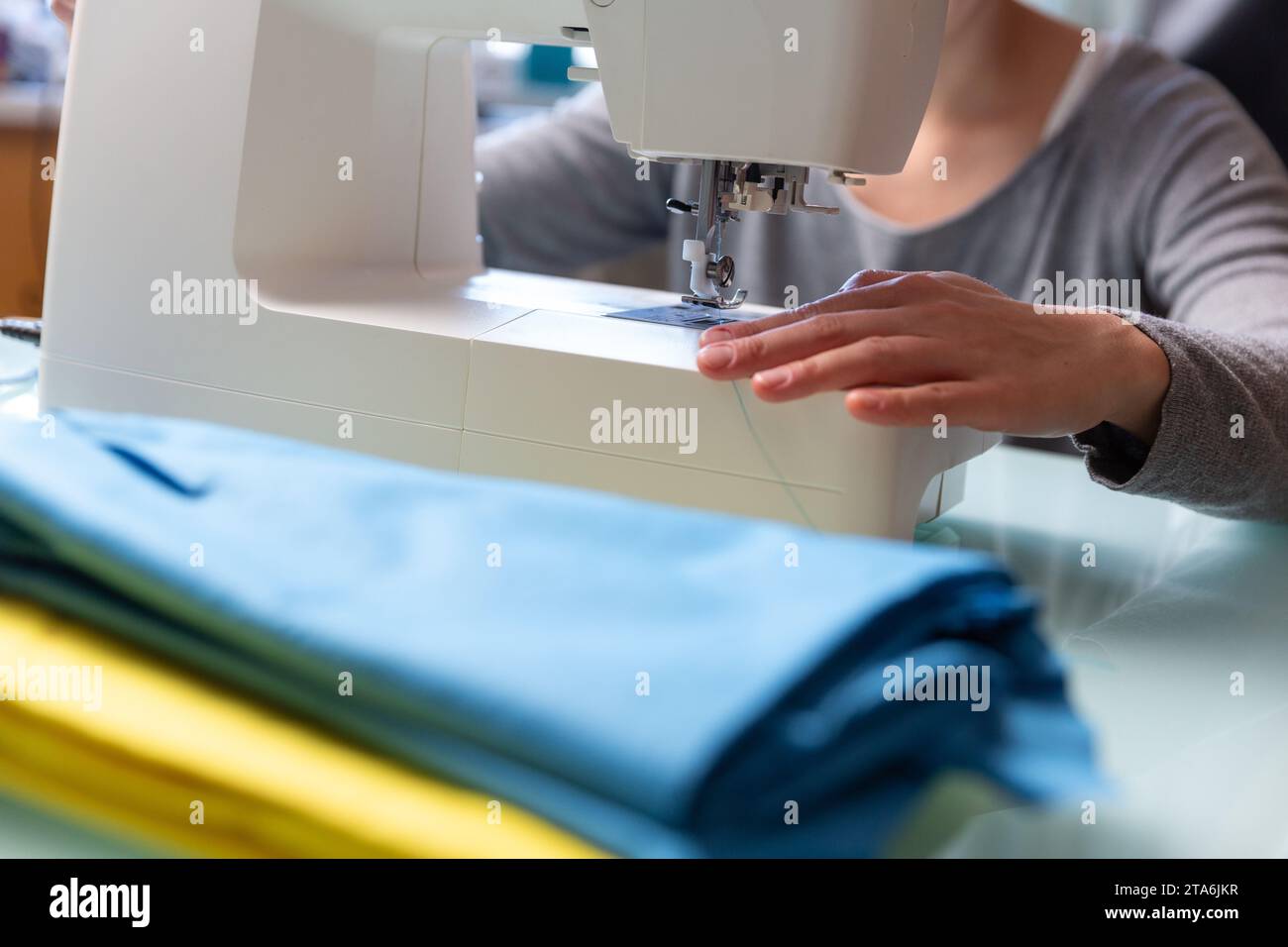 Primo piano delle mani femminili di Tailor che preparano la macchina da cucire. Foto Stock