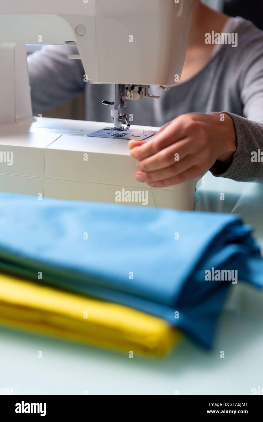 Primo piano delle mani femminili di Tailor che preparano la macchina da cucire. Foto Stock