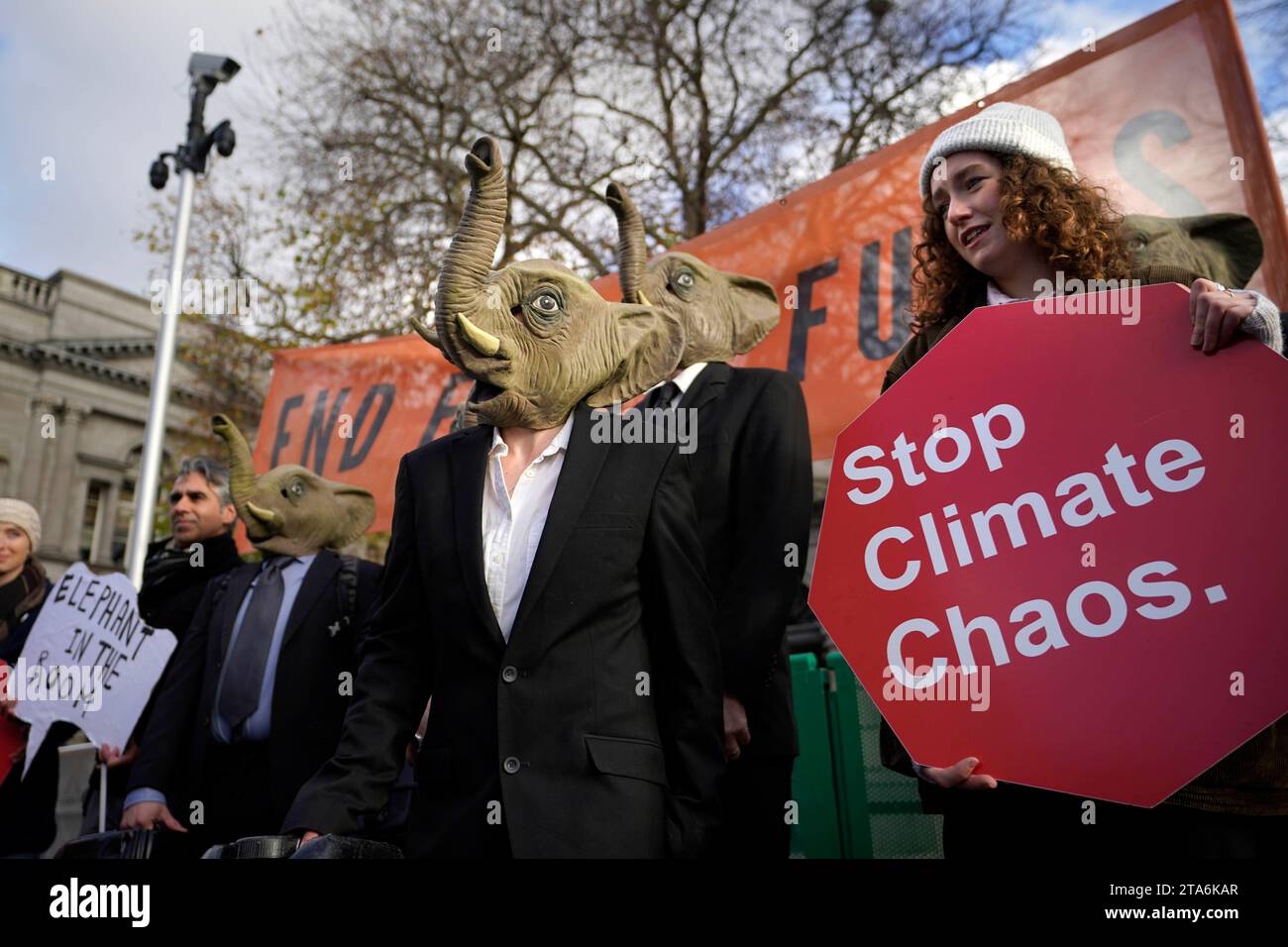 Fermare i membri del caos climatico, vestiti da CEO della Big Oil, con abiti da lavoro neri e con maschere di elefante fuori dalla Leinster House di Dublino per avvertire il governo irlandese che non deve lasciare che i combustibili fossili distruttivi dal clima siano l'elefante nella stanza dei colloqui sul clima della COP28 delle Nazioni Unite. Data foto: Mercoledì 29 novembre 2023. Foto Stock