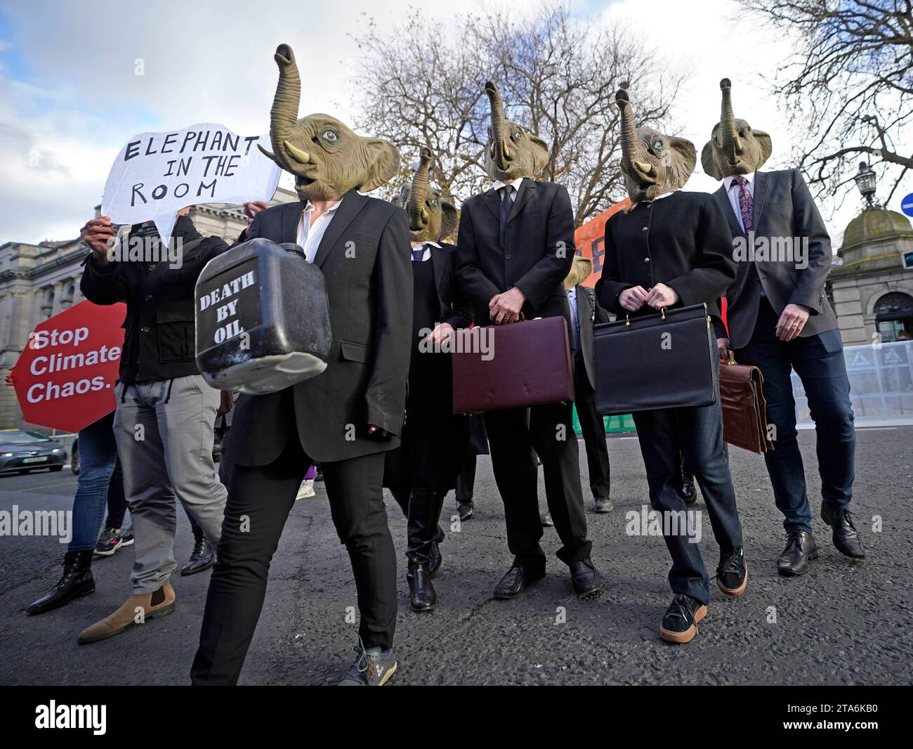 Fermare i membri del caos climatico, vestiti da CEO della Big Oil, con abiti da lavoro neri e con maschere di elefante fuori dalla Leinster House di Dublino per avvertire il governo irlandese che non deve lasciare che i combustibili fossili distruttivi dal clima siano l'elefante nella stanza dei colloqui sul clima della COP28 delle Nazioni Unite. Data foto: Mercoledì 29 novembre 2023. Foto Stock