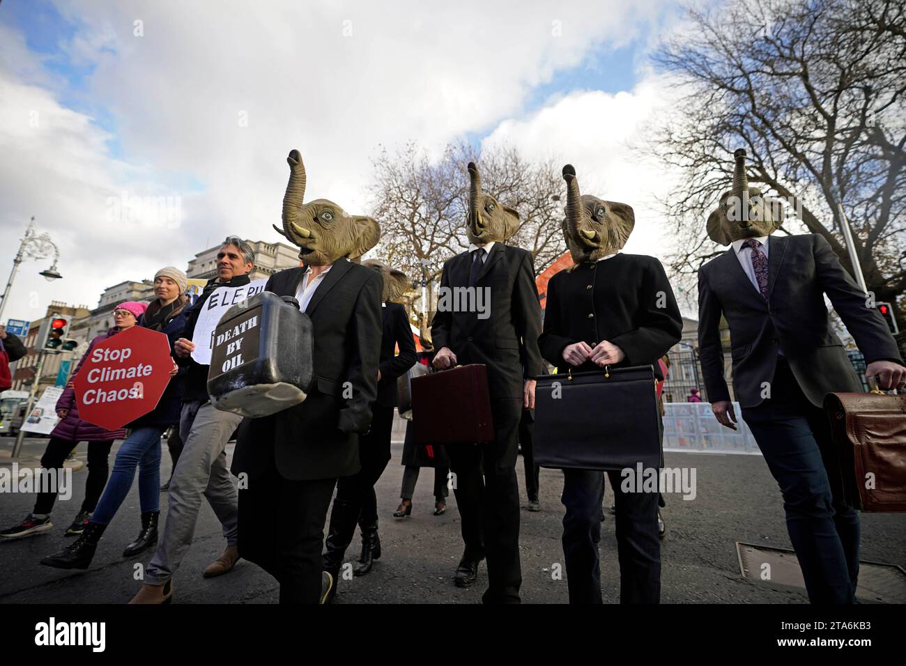 Fermare i membri del caos climatico, vestiti da CEO della Big Oil, con abiti da lavoro neri e con maschere di elefante fuori dalla Leinster House di Dublino per avvertire il governo irlandese che non deve lasciare che i combustibili fossili distruttivi dal clima siano l'elefante nella stanza dei colloqui sul clima della COP28 delle Nazioni Unite. Data foto: Mercoledì 29 novembre 2023. Foto Stock