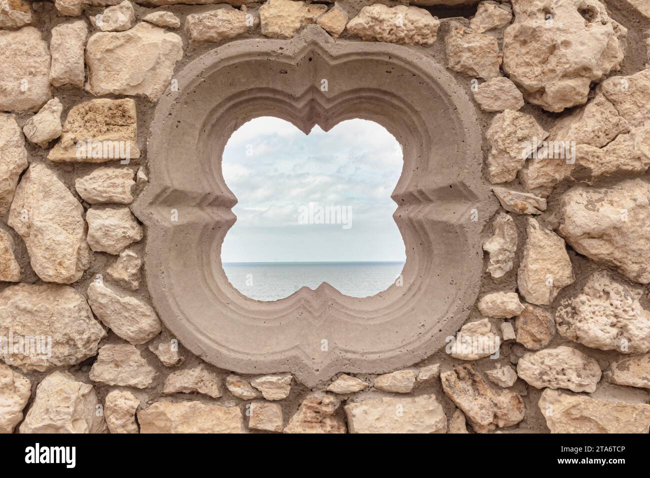 Finestra vuota rotonda - finestra a forma di fiore medievale in pietra rustica con oceano e cielo dietro - Tergniet Sud Africa Foto Stock